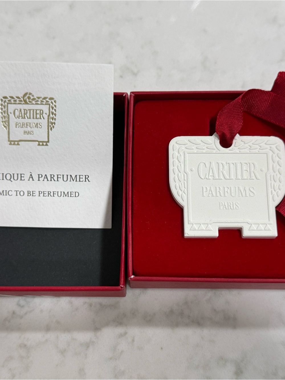 Cartier white ceramic perfume tag with red ribbon